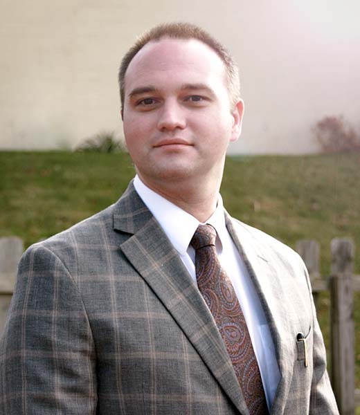 picture of our partner Tyler Mason in Plaid suit and tie.